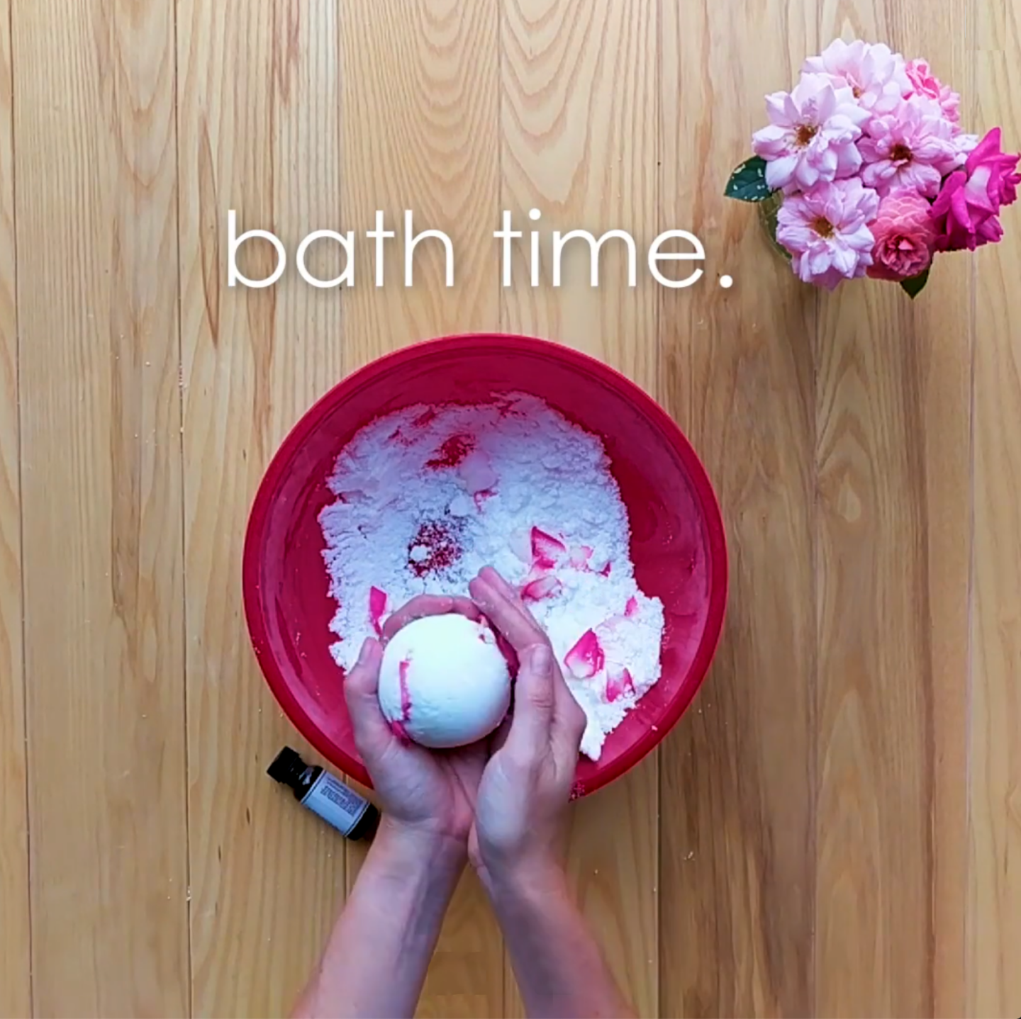 Hands holding bath bomb over bowl with ingredients